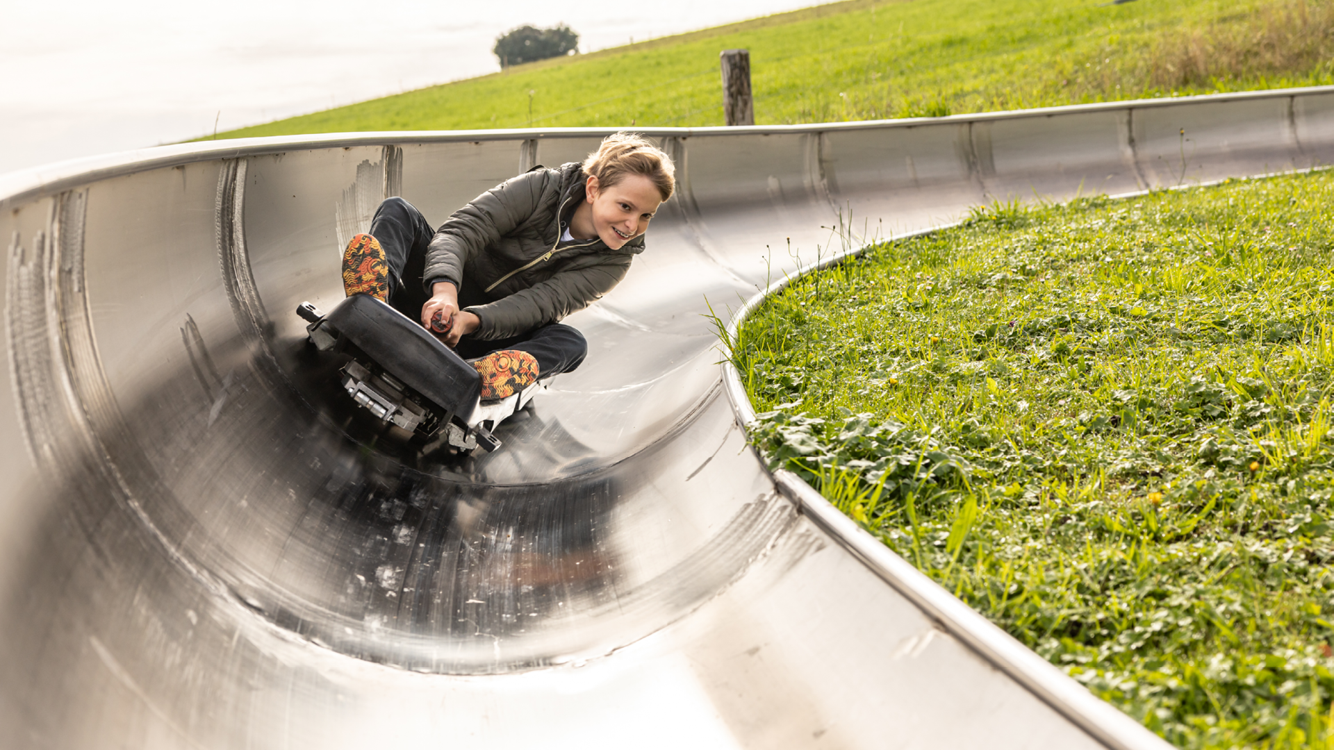 Boy leans heavily into a curve while sledding and laughs