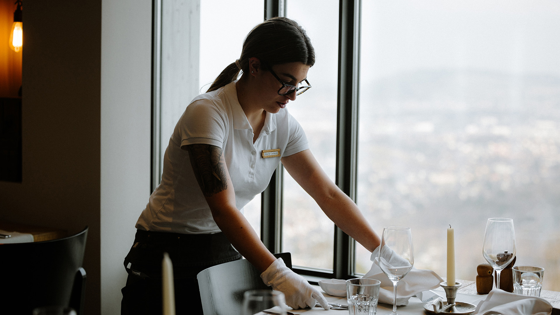 A young waitress sets the table.