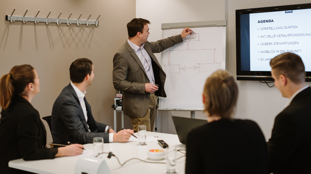 Eine Gruppe von Personen in einem Seminarraum, welche einen Sitzung halten.