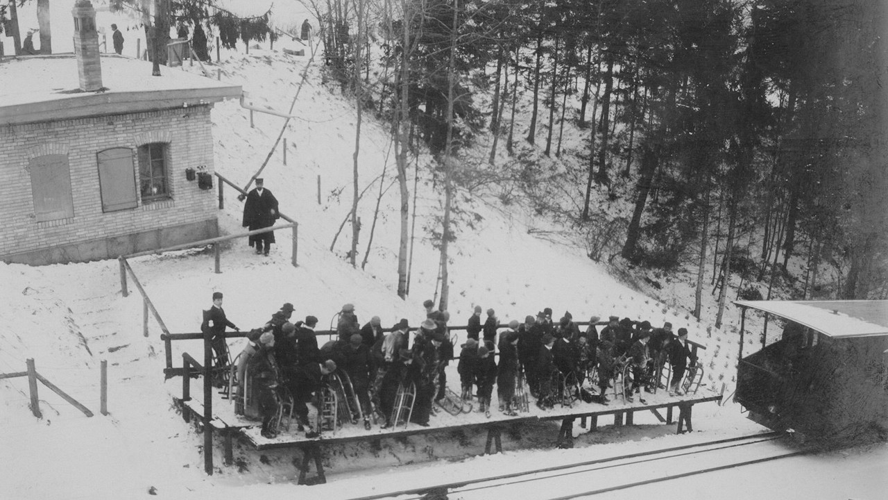 The Grünenboden stop in winter with many sledgers waiting for the Gurtenbahn railway in black and white.