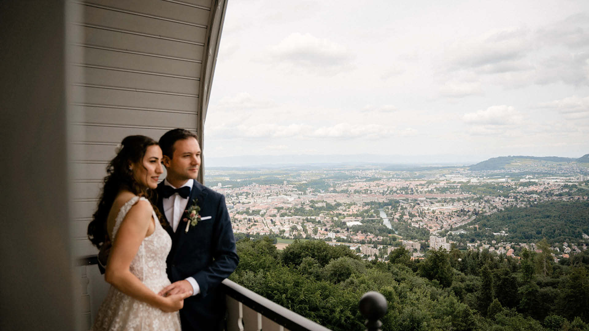 Ein Hochzeitspaar auf dem Balkon vom Kulmgebäude mit der Stadt Bern im Hintergrund.