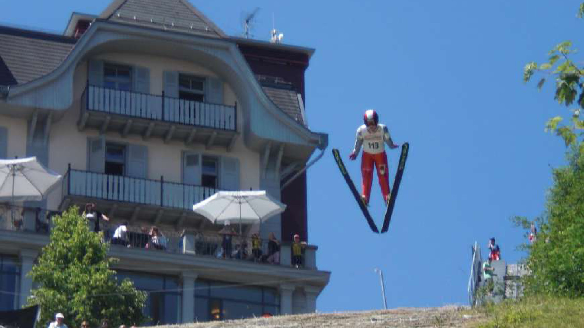 Skispringer auf der Skisprungschanze auf dem Gurten mit dem Kulm Gebäude im Hintergrund