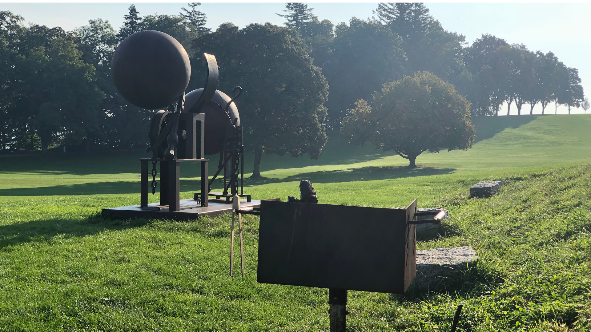 A fire pit next to a sculpture in the park.