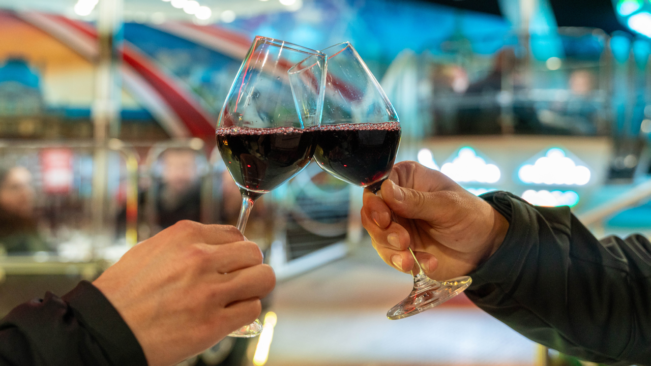 Zwei Personen welche mit Rotwein anstossen.