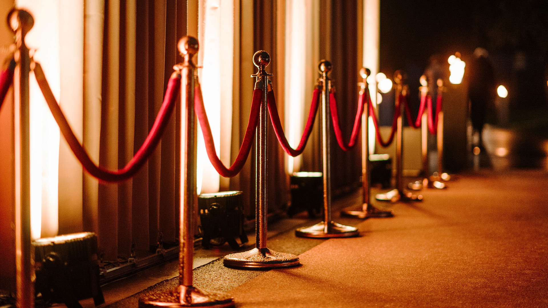 Roter Teppich am Boden sowie ein Leitsystem vor dem beleuchteten Pavillon