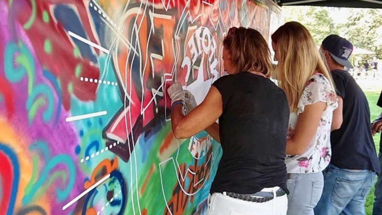 Drei Menschen sprayen auf Leinwand