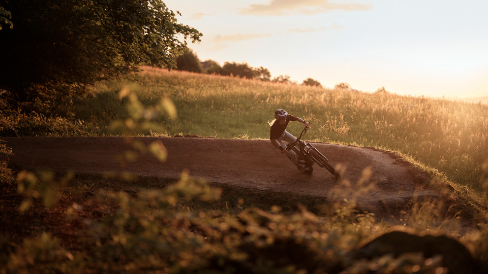 Person fährt Gurtentrail runter und liegt in Steilwandkurve