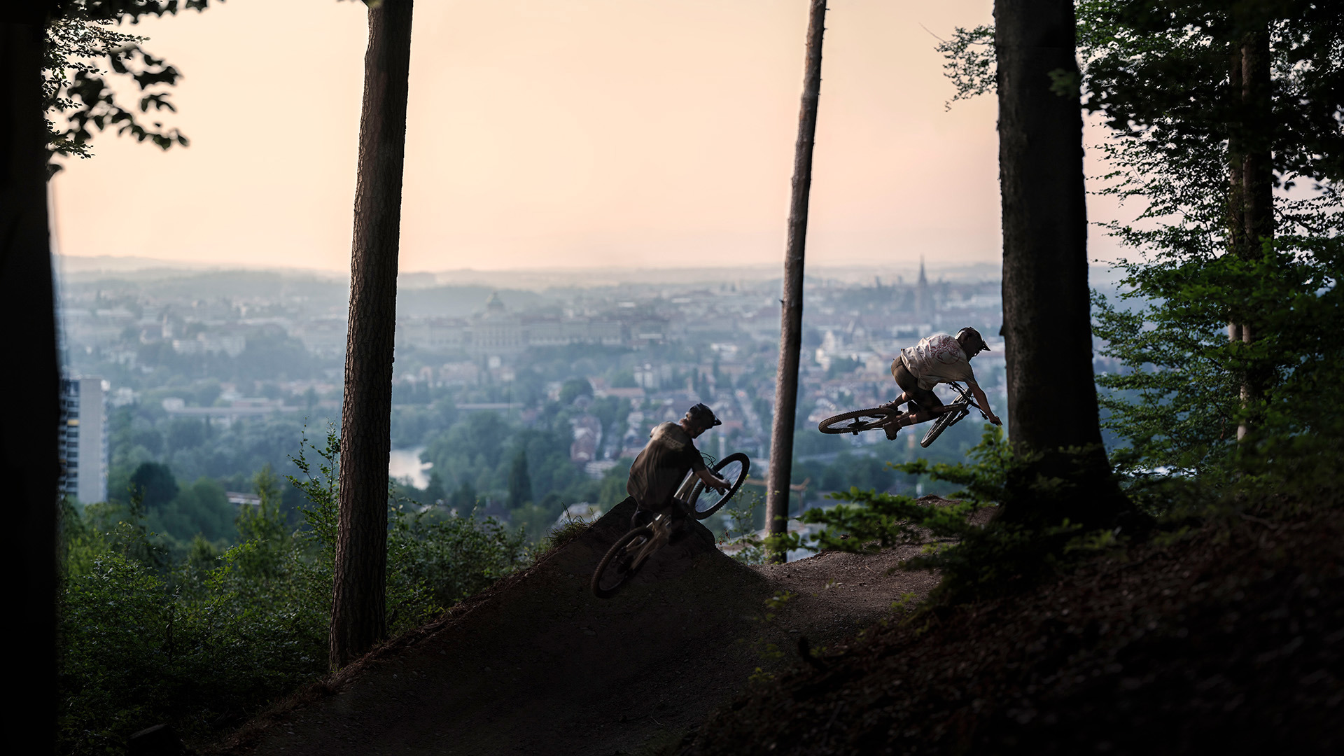 Mountainbiker fahren Gurtentrail herunter mit Sicht auf Stadt Bern