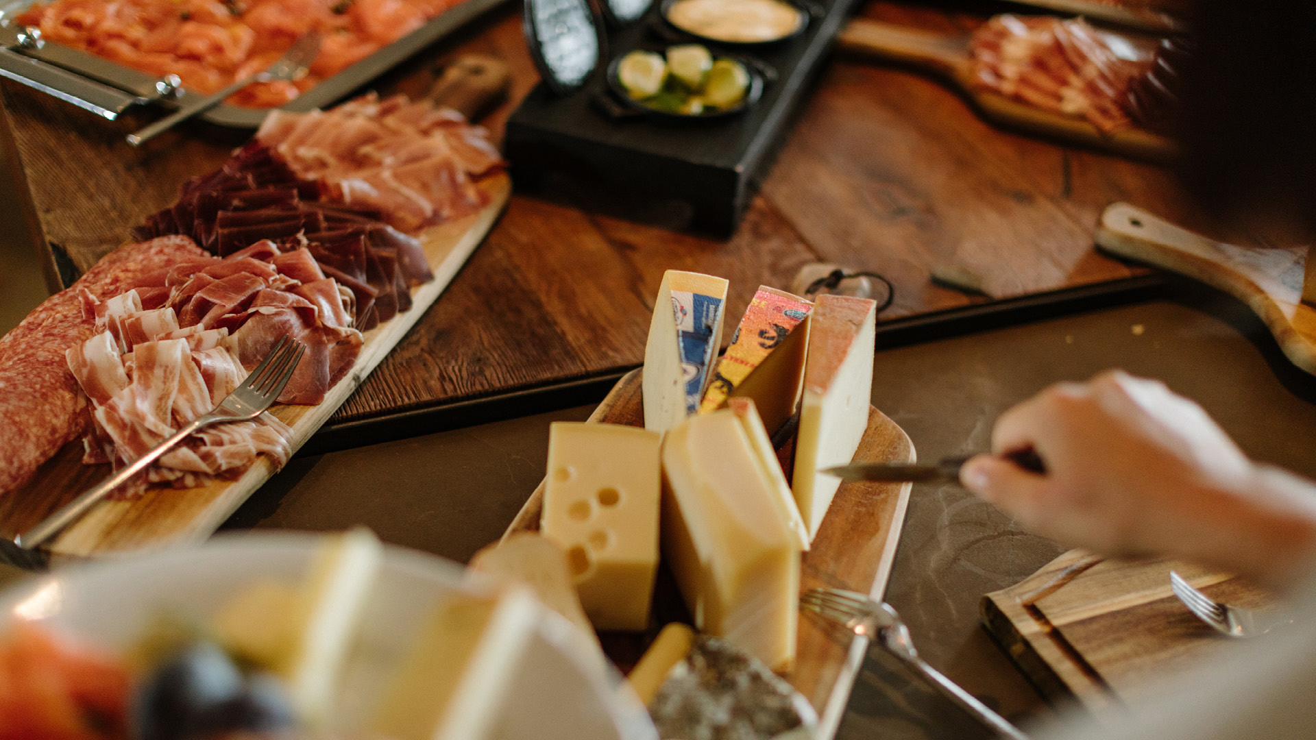 Une personne qui coupe du fromage avec un couteau sur une planche en bois.