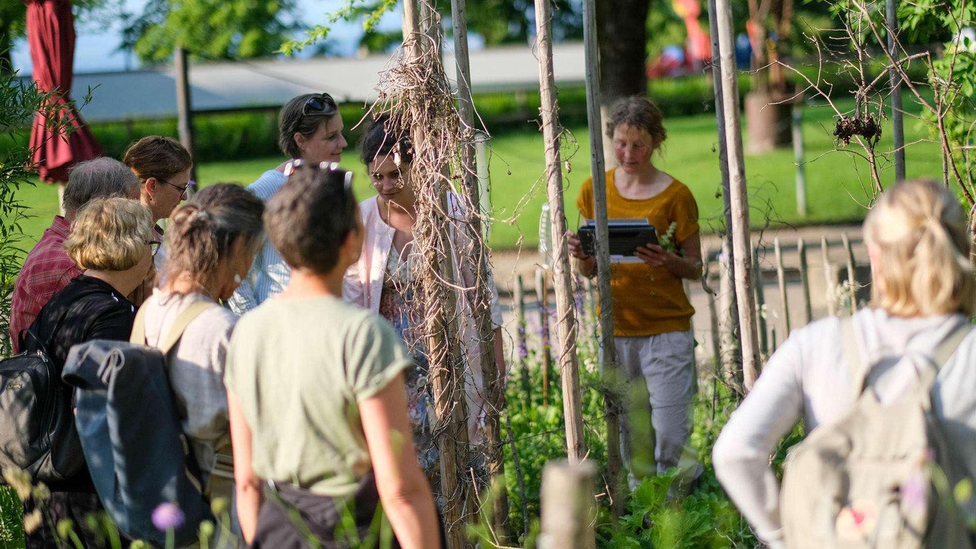 Several people are listening to a woman while looking at the plants in the Gurtengärtli.
