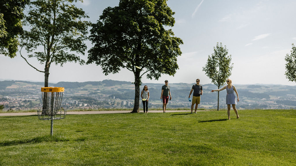 Un groupe joue au disc golf sur le Gurten avec vue sur la ville de Berne.