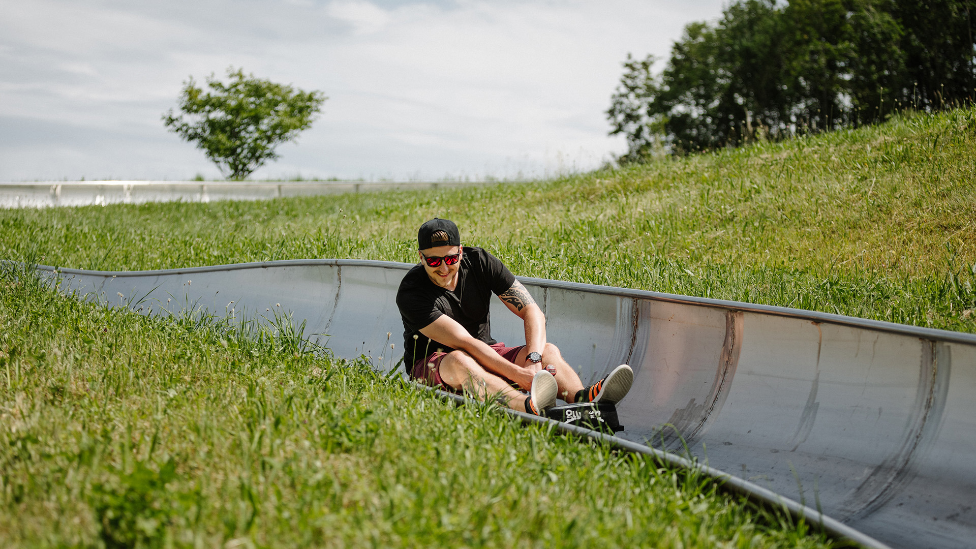 Person on a toboggan run wearing a black T-shirt and cap