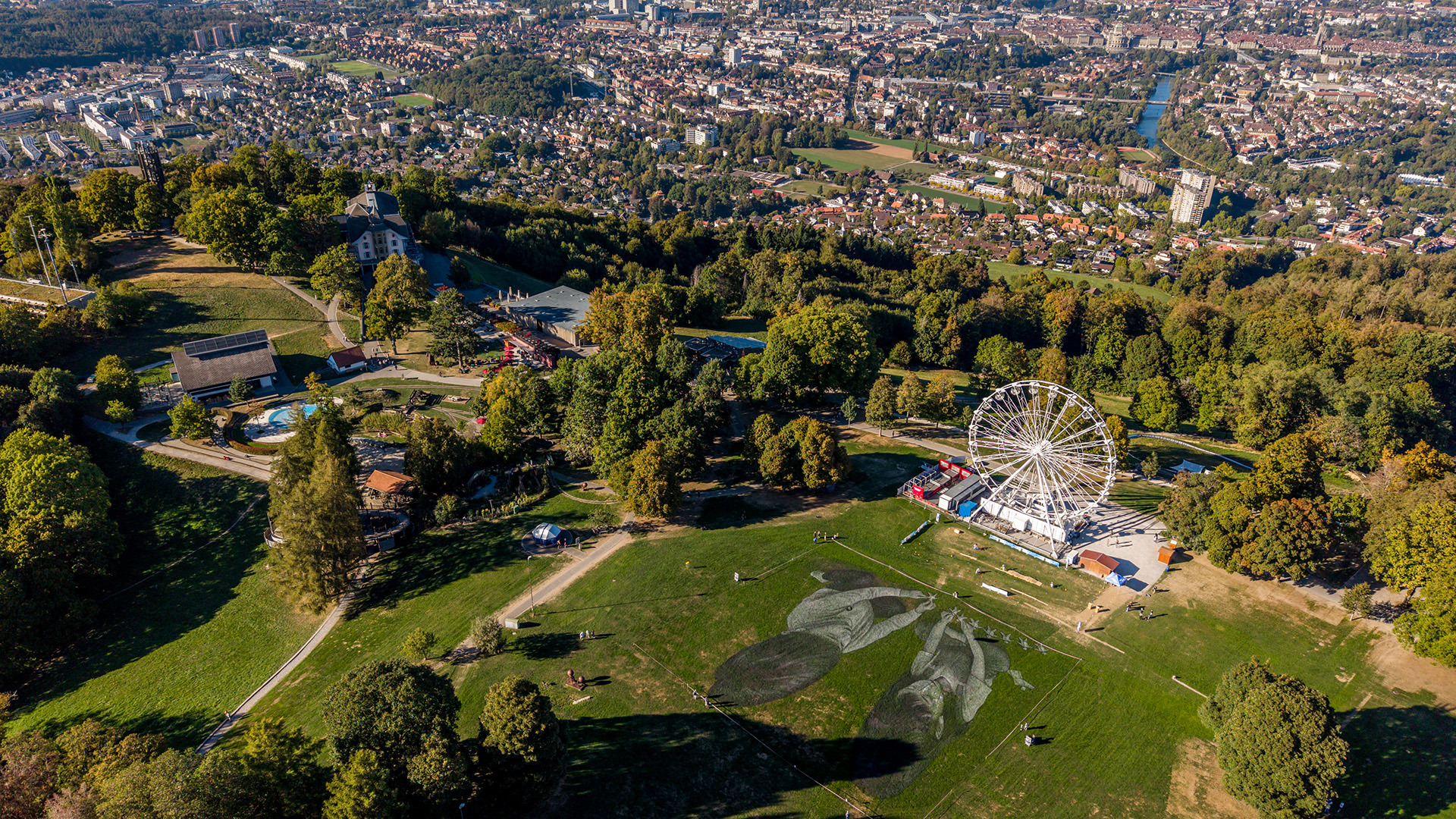 Luftaufnahme des Saype-Kunstwerks auf dem Gurten mit Blick über die Stadt Bern.
