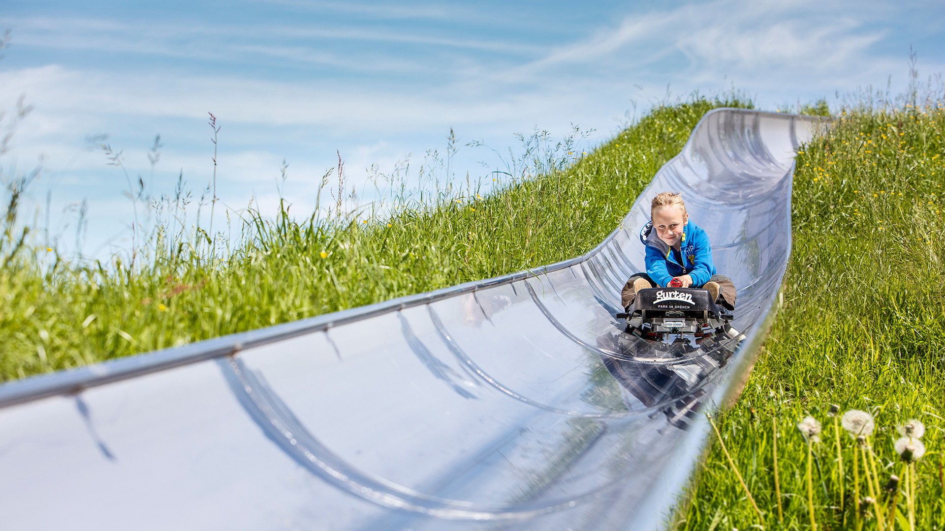 Child on a toboggan run wearing a blue jacket
