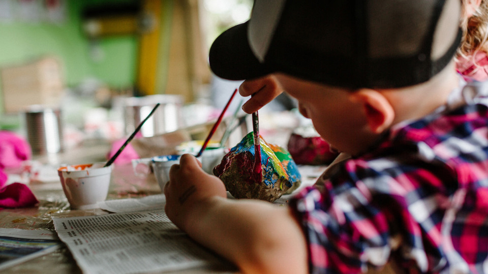 A small child painting a stone.