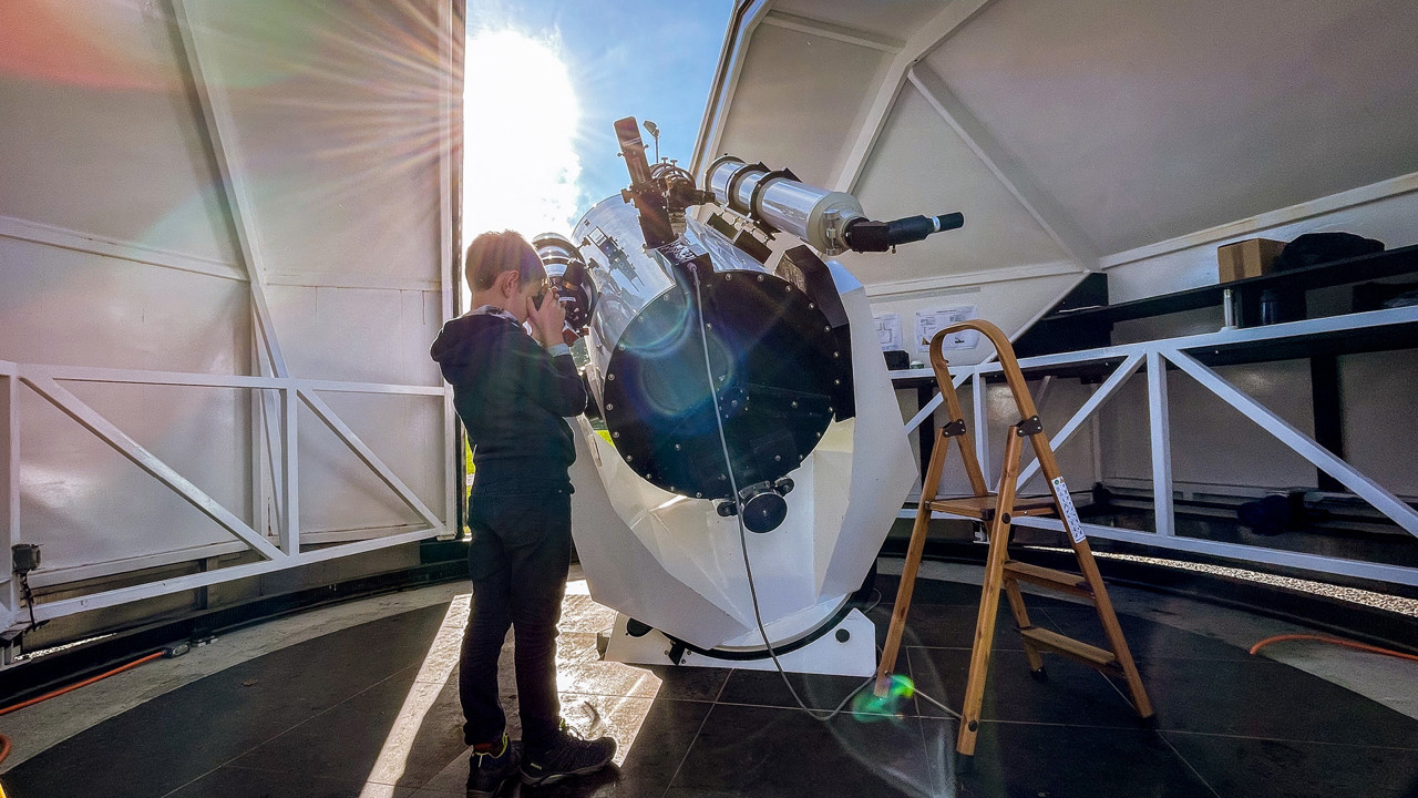 Un enfant qui observe le soleil à travers un télescope.