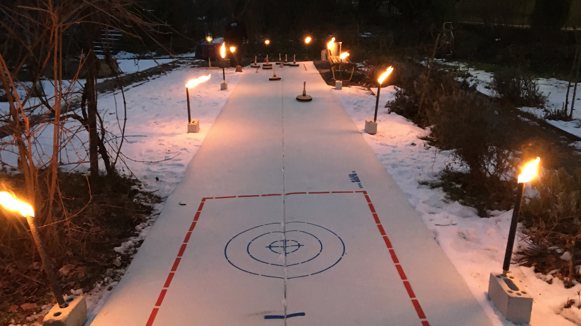 Curling Bahn mit Fackeln und Bäumen