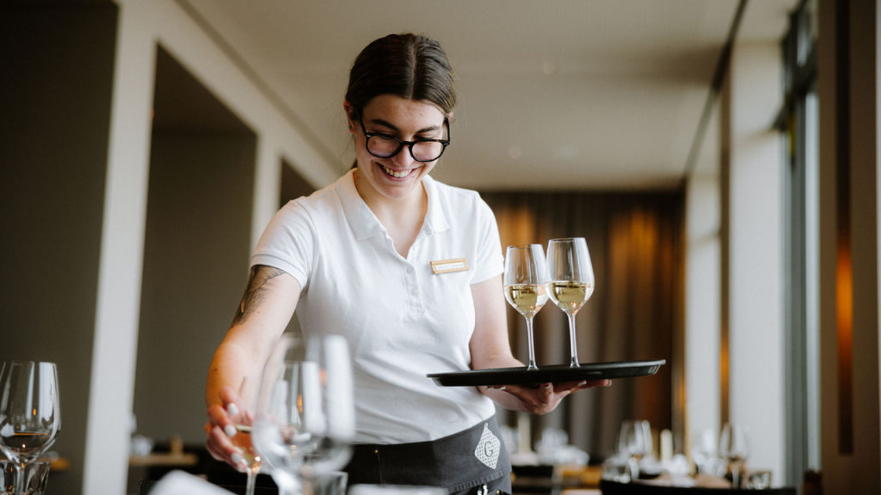 A woman serving wine glasses at Gurtner's restaurant.