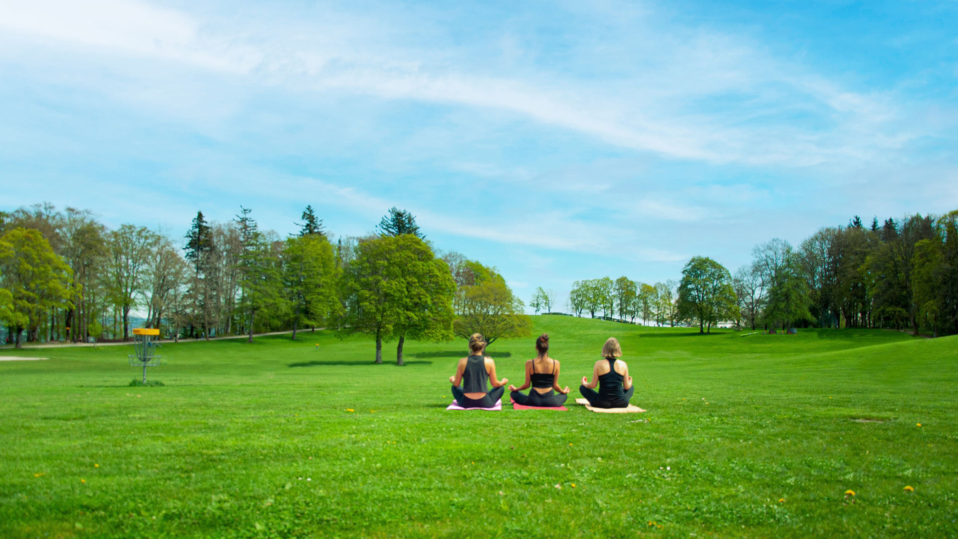 Three women are doing yoga on the Gurten meadow.